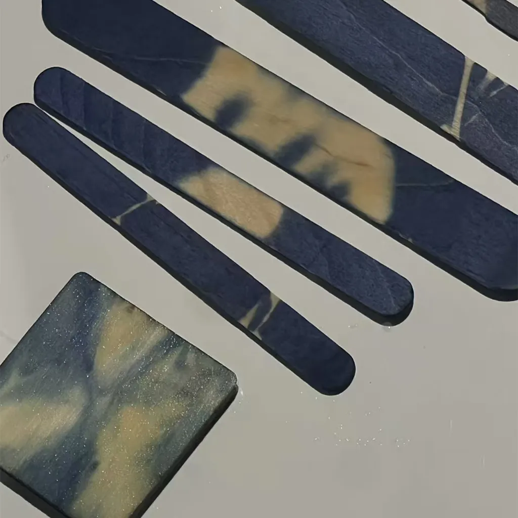 Strips of freshly indigo-dyed cotton drying on a table, showing deep blue and cream shibori patterns.